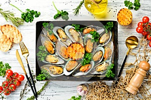 Cooked mussels with garlic, parsley and lemon. Seafood. On a white wooden background.