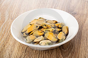 Cooked mussels in plate on wooden table