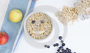 Cooked oatmeal with blueberries and apples. Funny face made of fruit. Art food