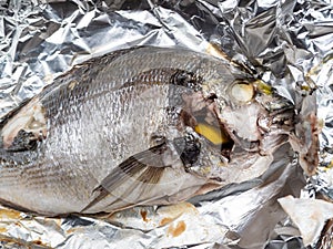 Cooked Orata fish stuffed by lemon baked in foil
