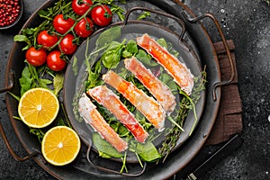 Cooked Organic Alaskan King Crab Legs with Butter, on black dark stone table background, top view flat lay