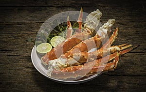 Cooked Organic Alaskan King Crab Legs with Butter and lemons, Alaskan King Crab on vintage wooden background.