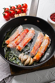 Cooked Organic Alaskan King Crab Legs with Butter, in cast iron frying pan, on white stone table background