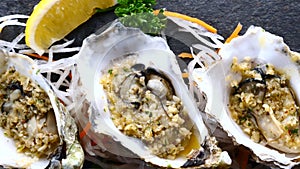 Cooked Oysters in Half Shells on Black Textured Slate Background, Top View