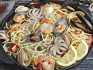 Cooked pasta with clams, shrimps, baby octopus, mussels tomato on a frying pan , spaghetti. Close up