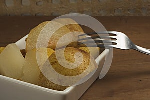 Cooked pear cut into slices, served in a small white plate, a very everyday food in season in Mexico, consumed as a dessert or bre