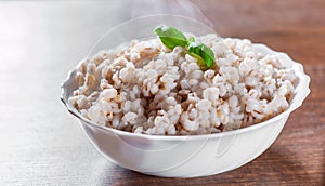 Cooked pearl barley in bowl on a wooden table