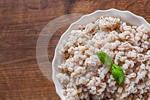 Cooked pearl barley in bowl on a wooden table