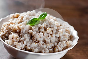 Cooked pearl barley in bowl on a wooden table