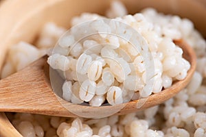 Cooked peeled barley grains in wooden bowl