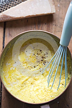 Cooked polenta dish  with parmesan  butter  salt and pepper . Polenta is made when cornmeal is boiled in water and chicken stock.