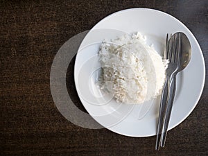 Cooked rice in bowl with spoon and dishcloth on old wooden table .