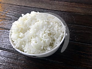 Cooked rice bowl on wooden table.