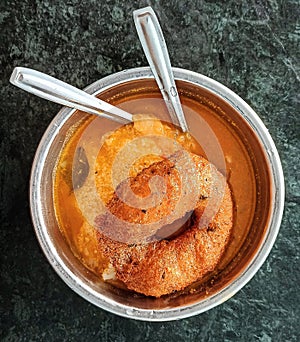 Cooked rice dipped in sambar along with Medu vada photo