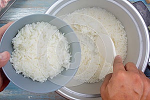 Cooked rice on plastic ladle in electric rice cooker