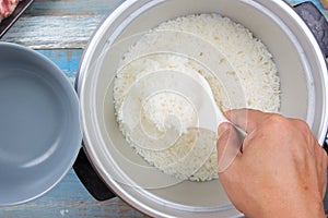 Cooked rice on plastic ladle in electric rice cooker