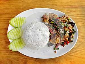 Cooked rice serving with fried fish with garlic and pepper, serving on round white plate