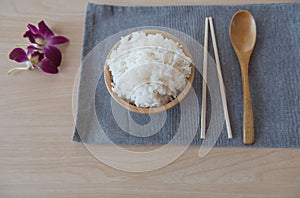 Cooked rice in a wooden bowl and spoon ,chopsticks on a wood background.