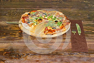 Cooked pizza and cutlery set on the old rustic table