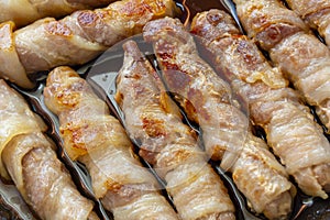 Cooked sausages in bacon. bacon roll close up. Abstract background with bacon