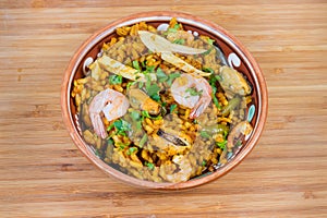 Cooked seafood paella in bowl on wooden surface