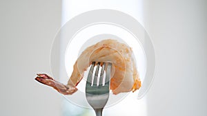 Cooked shrimp on fork on white blurred background