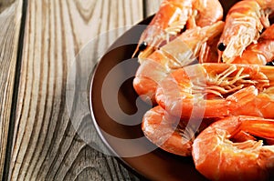 Cooked shrimp on a plate on a wooden background close-up