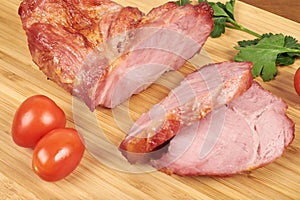 Cooked sliced pork ham steak on wooden cutting board.