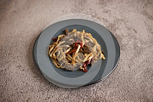Cooked soba on a plate next to spices, pepper and garlic
