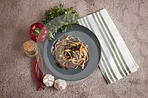 Cooked soba on a plate next to spices, pepper and garlic