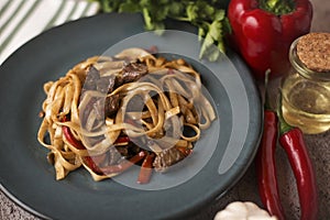 Cooked soba on a plate next to spices, pepper and garlic