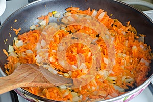 Cooked soup ingredient. Sauteed chopped onions and grated carrots for soup in a frying pan. fried vegetables