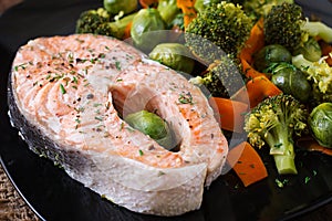 Cooked on steam salmon steak with vegetables.