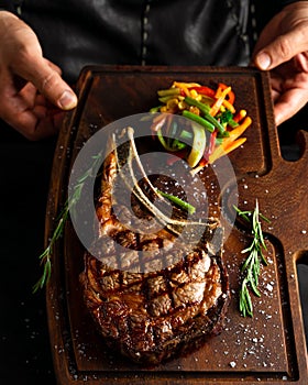 Cooked Tomahawk long bone ribeye steak on a serving board photo