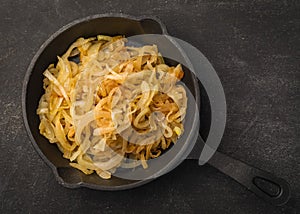 Cooked vegetables on black plate and dark background, baked onion