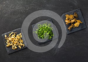 Cooked vegetables on black plate and dark background, garlic, green onion, mushroom.