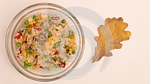 Cooked white rice with colorful vegetables in glass bowl, top view.