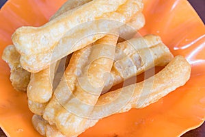 Cooked youtiao or Asian doughnut breadstick in orange plate close-up