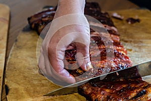 Cooker's hand cut tasty smoked pork ribs on wooden desk