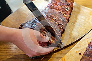Cooker's hand cut tasty smoked pork ribs on wooden desk
