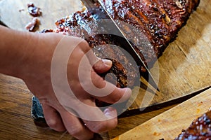 Cooker's hand cut tasty smoked pork ribs on wooden desk