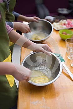 Cookery scene with female hands beating eggs with eggbeater in m