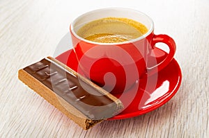 Cookie with chocolate and caramel, cup with coffee espresso in saucer on table