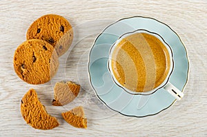 Cookie with chocolate, pieces of cookie, coffee espresso in cup on saucer on table. Top view