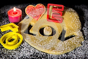 Cookie dough and cookie cutter on a black stone with icing sugar