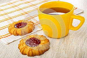 Cookie on napkin, cookies with jam, cup with hot tea on wooden table