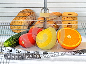 Cookies are in the cage locked with padlock. Vegetables, fruits and measuring tape with centimeters and inches are in the