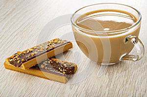 Cookies with caramel, cocoa and cereals, cup of coffee with milk on wooden table