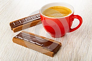 Cookies with chocolate and caramel, cup with coffee espresso on wooden table