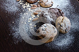 Cookies with chocolate on dark background with sugar powder, oat flakes, seasame and almond. Copyplace, place for text. Sweets